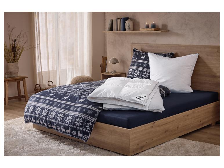 Chambre avec un lit en bois, une parure de lit à motif hivernal et une couette blanche.