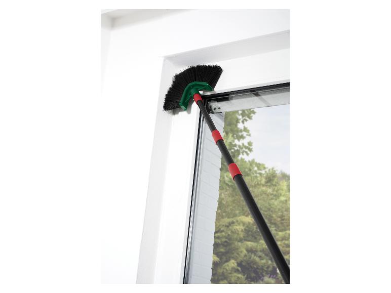 Brosse à toile d'araignée avec manche télescopique nettoyant un cadre de fenêtre.