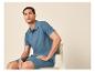 Homme en polo et short bleus assis sur une chaise.