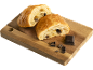 Deux pains au chocolat sur une planche en bois avec des morceaux de chocolat.