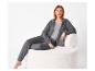 Femme en ensemble de loungewear gris assise sur une chaise blanche texturée.