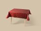 Nappe de Noël rouge avec motifs festifs dorés sur une table en bois.