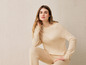 Une femme portant un pull et un pantalon en tricot beige.