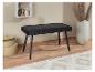 Un banc en velours noir avec des pieds en bois dans un intérieur moderne.