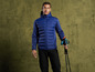 Un homme en veste bleue à capuche et des bâtons de randonnée.