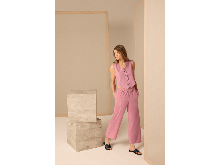 Femme portant un gilet en lin rose et un pantalon large assorti.