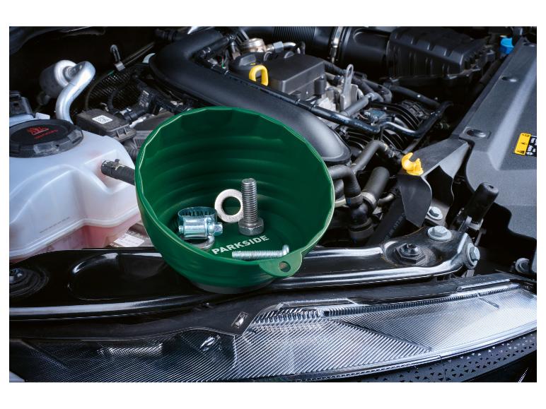 Bol magnétique vert avec boulons et collier de serrage dans un compartiment moteur.