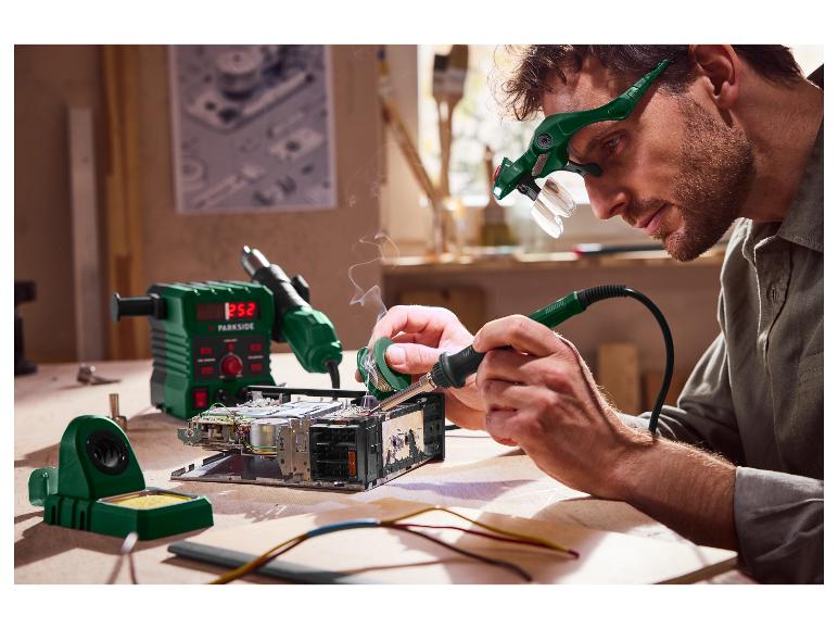 Homme soudant de l'électronique avec l'équipement Parkside, y compris une station de soudage et des lunettes loupes.