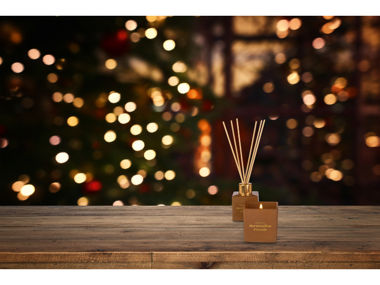 Bougie et diffuseur Marshmallow Fireside sur table en bois avec lumières de Noël.