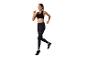 Femme courant en leggings et soutien-gorge de sport noirs.