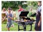 Un barbecue à gaz avec des hamburgers, des légumes et un garçon qui court