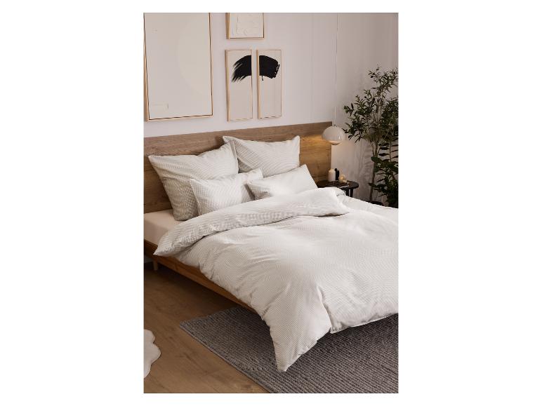 Chambre avec un lit doté de linge de lit clair, une table de chevet et de l'art mural.