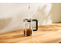 De l'eau versée dans une cafetière à piston avec du café sur une table en bois.