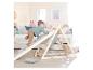 Enfant grimpant sur un triangle d'escalade en bois avec rampe dans une chambre d'enfant.