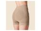 Femme en short gainant taille haute beige, avec détails côtelés et zones de compression.