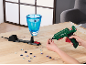 Pistolet à colle chaude décorant un vase en verre avec des gemmes sur une table en bois.