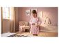 Fille en robe rose met un dessin de soleil dans sa poche, dans une chambre d'enfant.