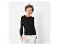 Une femme portant un pull noir et un pantalon blanc.