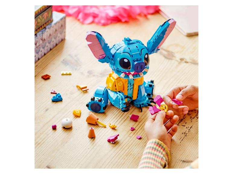 Enfant assemblant un jouet de construction Stitch en briques, avec des pièces éparpillées.
