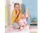 Fille riante avec poupée assise sur un pot, dans un décor de salle de bain.