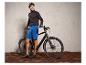 Un homme en tenue de vélo s'appuie sur un vélo électrique noir.