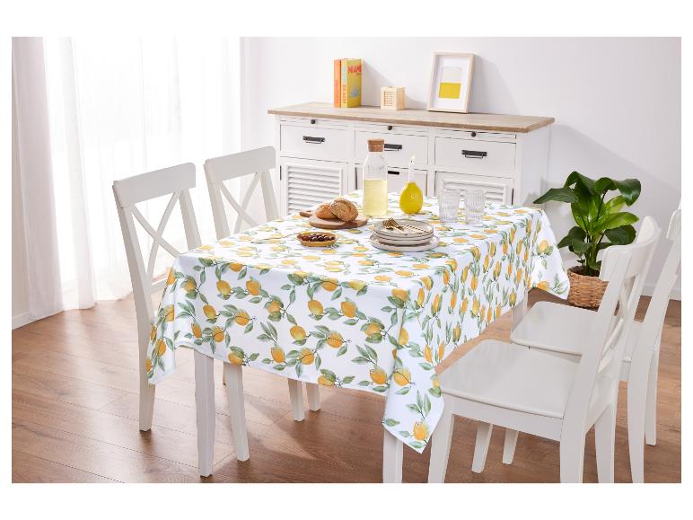 Nappe à motif citron et chaises blanches pour une table de salle à manger.