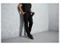 Un homme porte un pantalon de survêtement, un t-shirt et des chaussures noirs.