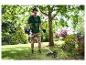 Homme en équipement de sécurité utilisant une débroussailleuse pour tailler l'herbe dans un jardin.