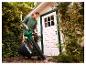 Une femme utilise l'aspirateur-souffleur de feuilles sans fil PARKSIDE® dans le jardin.