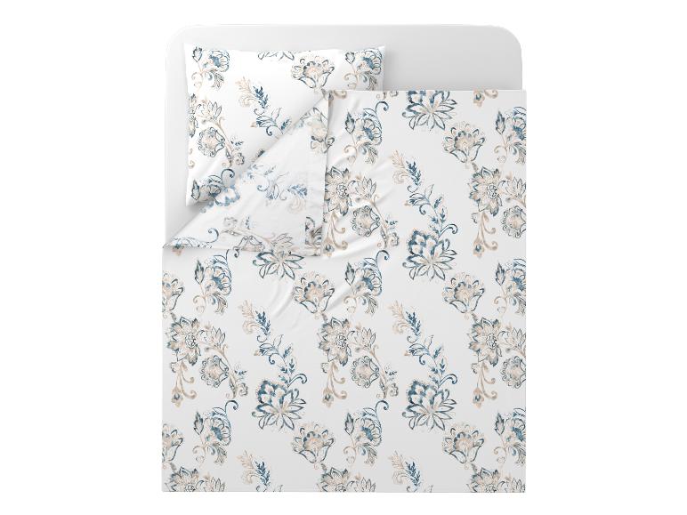 Parure de lit à motif floral bleu et beige sur un lit blanc.