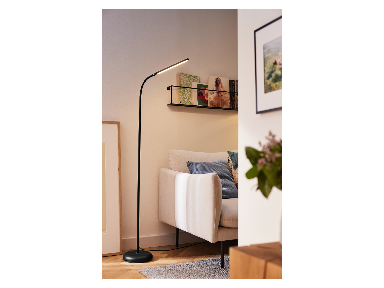 Un lampadaire noir à bras courbe éclaire un salon moderne.