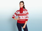Une femme portant un pull rouge à motif ski et un jean bleu.