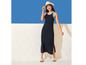 Une femme porte une robe maxi noire avec des rayures blanches et un chapeau blanc.