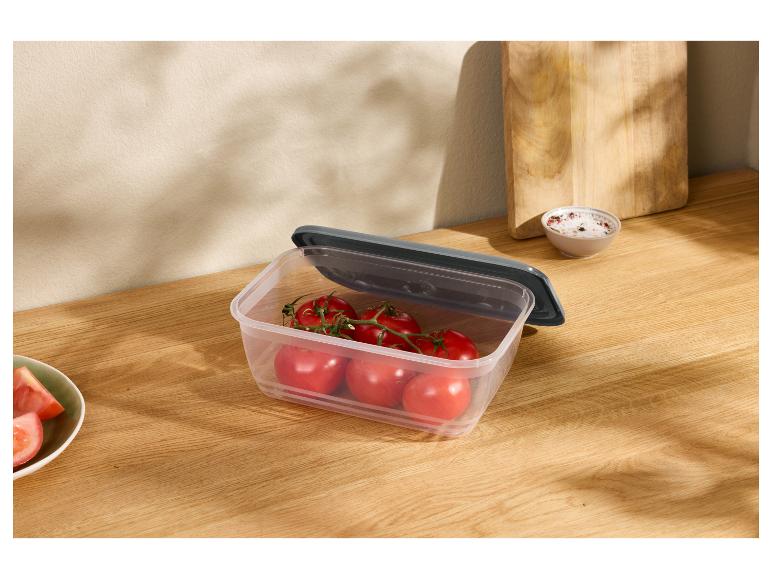 Récipient alimentaire avec des tomates sur un comptoir en bois.