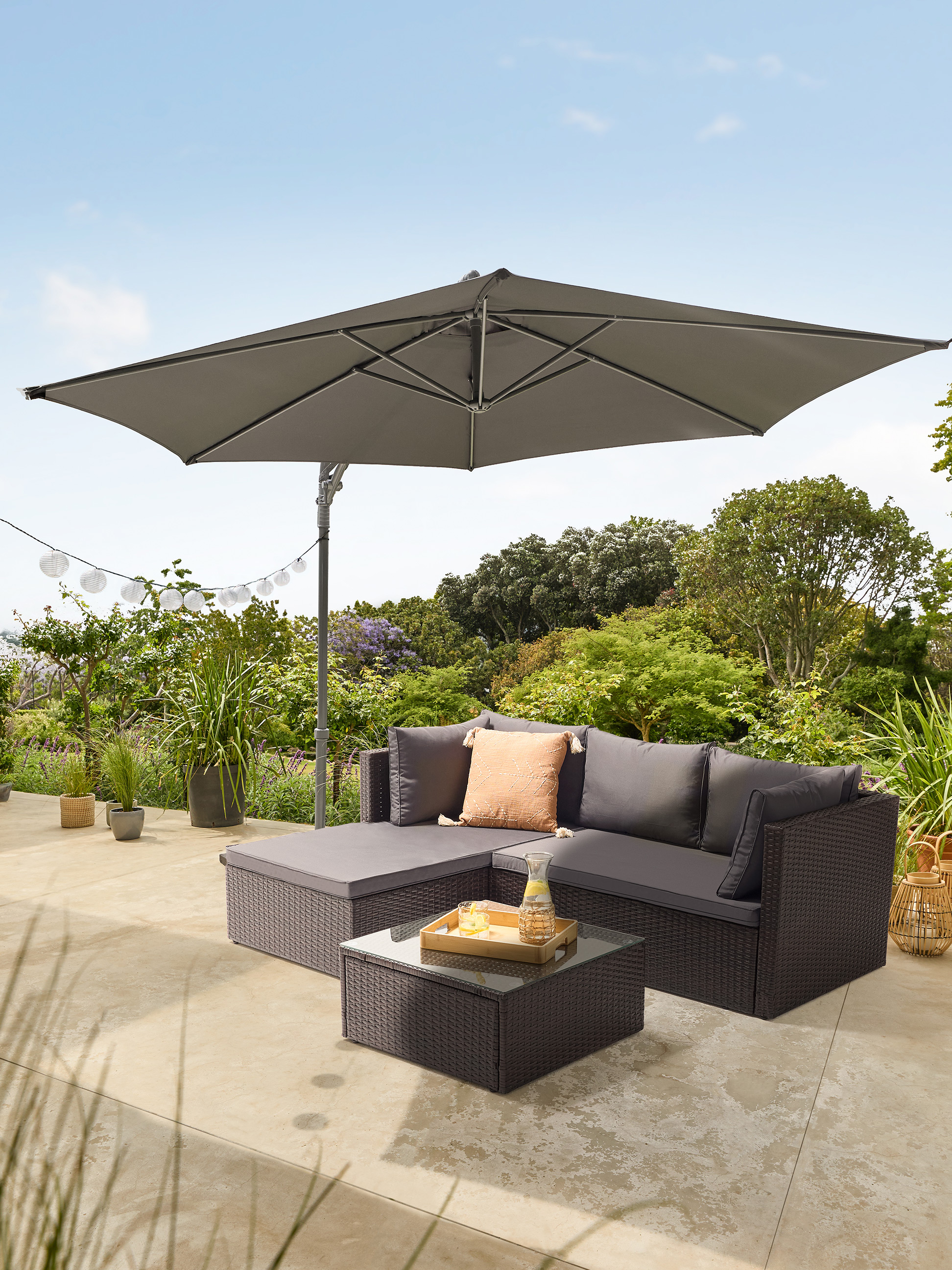Ensemble canapé de jardin avec parasol et table basse sur une terrasse.