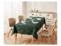 Une nappe vert foncé à motif d'arbres de Noël, dressée avec des couverts, des verres et des serviettes.