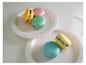 Mini-ventilateurs colorés en forme de macaron sur des assiettes blanches.
