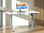 Un bureau blanc avec un moniteur, un clavier et un réglage de hauteur.