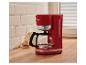 Cafetière rouge sur un comptoir de cuisine, avec des biscuits et du lait en arrière-plan.