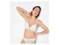 Femme en bralette et culotte en dentelle blanche, posant sur fond blanc.