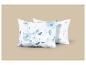 Deux oreillers blancs avec un motif floral aquarelle bleu sur fond beige.