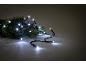Guirlande lumineuse LED blanche sur une branche de sapin, sur fond sombre.