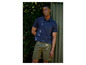 Un homme porte un polo bleu et un short vert.