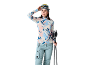 Femme en tenue de ski: haut thermique imprimé, pantalon bleu, bonnet et lunettes.