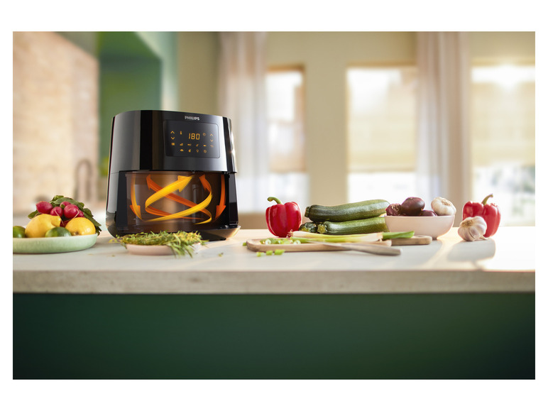 Une friteuse à air Philips avec des légumes sur un comptoir.