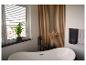 Salle de bain moderne avec baignoire îlot, mur à lattes en bois et plante verte.