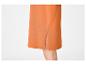 Détail d'une jupe orange avec une fente latérale, montrant une partie de la jambe.