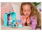Une fille joue avec une maison de poupée et des poupées de la série 'Rainbow High'.