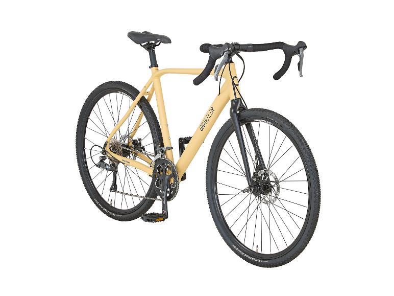 Vélo de gravel beige avec pneus et guidon noirs, portant l'inscription 'GRAVELER' sur le cadre.