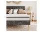 Un cadre de lit gris avec un matelas blanc et un tapis beige.